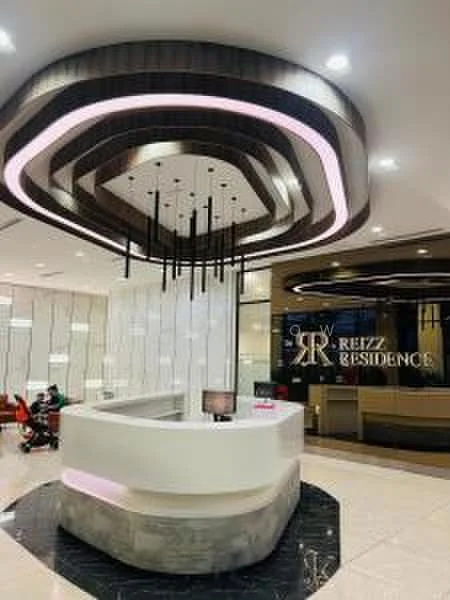 Room features: reception desk with curved design, white countertop, black and white tiled flooring, modern ceiling with layered design, LED strip lighting, hanging pendant lights, glass partition walls, decorative wall with branding, seating area with chairs, reception area with computer monitor; style: modern.