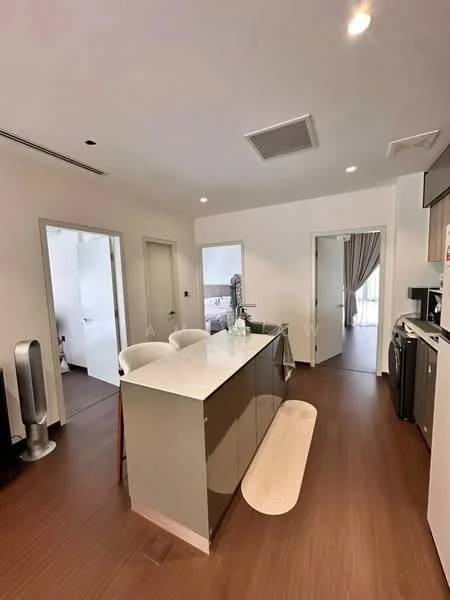 Kitchen features: white cabinetry, grey countertop, stainless-steel sink, chrome pull-down faucet, built-in oven, freestanding washing machine, refrigerator, pendant lighting, island with seating, wooden flooring, open layout, wall-mounted air conditioning unit; style: modern. Room features: doorway leading to other rooms, light-colored walls, curtains visible in background.