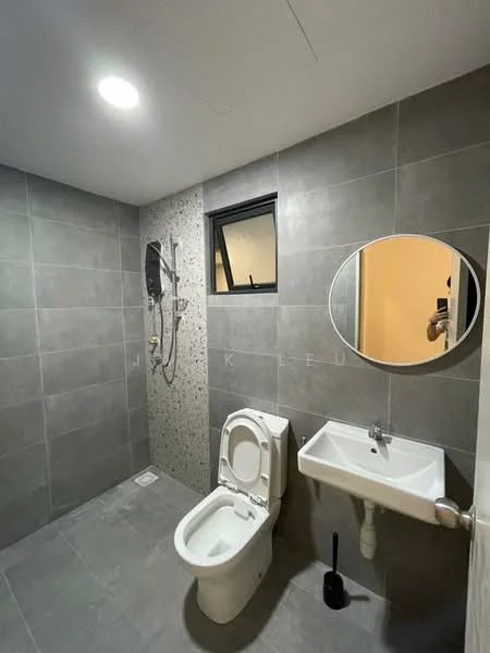 Bathroom features: grey ceramic tile flooring, grey tiled walls, shower area with glass partition, rain shower head, handheld shower, wall-mounted shower control, round mirror, white pedestal sink, one-piece toilet, black toilet brush holder, window for natural light, recessed ceiling lights; style: modern.