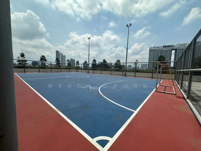 Exterior type: sports court; features: outdoor basketball court, blue and red court surface, white boundary lines, basketball hoop, surrounding fencing, city skyline in background, overhead floodlights, manicured landscaping around court; style: modern.