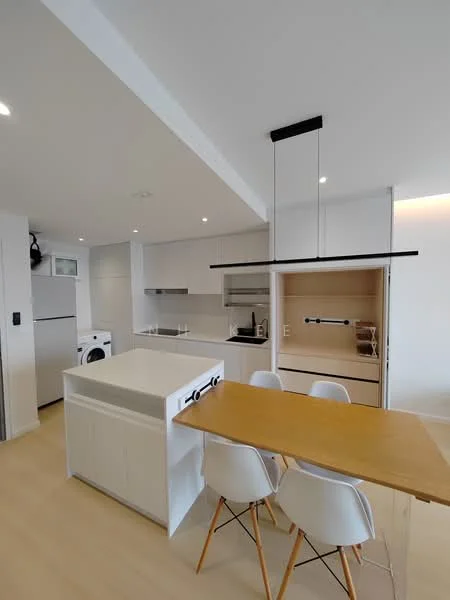 Kitchen features: white cabinetry, grey countertop, island with seating, built-in oven, stainless-steel sink, chrome pull-down faucet, refrigerator, washing machine, pendant lighting, open shelving, wood dining table, white dining chairs, light wood flooring, recessed downlights; style: modern.