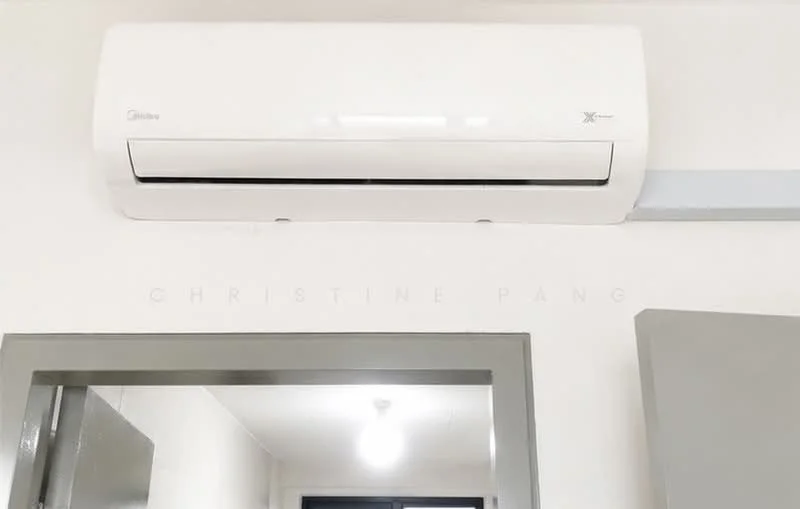 Room features: wall-mounted split AC, white painted walls, grey door frame, light fixture on ceiling.