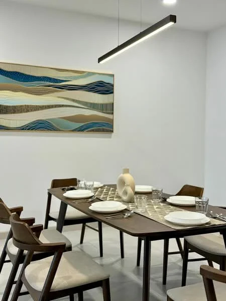 Dining features: rectangular wooden dining table, 6 upholstered dining chairs, decorative table runner, set of white plates, set of drinking glasses, abstract wall art, pendant light fixture, white painted walls, grey tile flooring; style: modern.