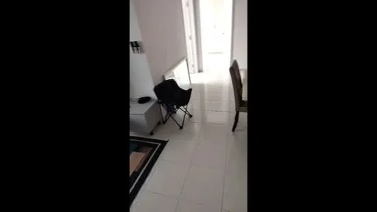 Room features: white painted walls, light-colored tiled flooring, black folding chair, dining table, area rug, doorway leading to another room.