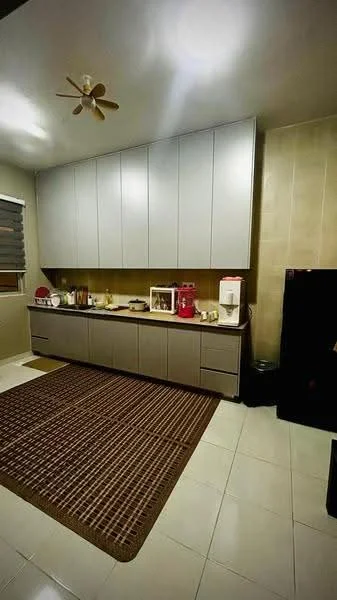 Kitchen features: grey cabinetry with upper cabinets, white countertop, stainless-steel sink, built-in refrigerator, microwave, coffee machine, kettle, 4-burner gas hob, white tiled backsplash, cream tiled flooring, 5-blade ceiling fan, area rug with geometric pattern, window with blinds; style: modern.