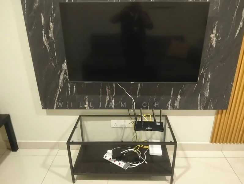 Living features: wall-mounted flat-screen TV, black marble feature wall, glass coffee table, metal frame for coffee table, visible power strip, network router, cables and wires visible, light-colored tile flooring, neutral wall color, sofa partially visible; style: modern.