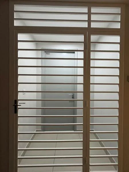 Room features: white painted walls, grey door, sliding glass door with horizontal slats, tile flooring, recessed lighting, neutral color scheme; style: modern.