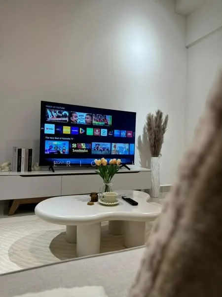 Living features: wall-mounted TV, white TV console, coffee table, decorative vase with dried flowers, fresh flowers in vase, neutral-colored area rug, light-colored walls, soft lighting; style: modern.