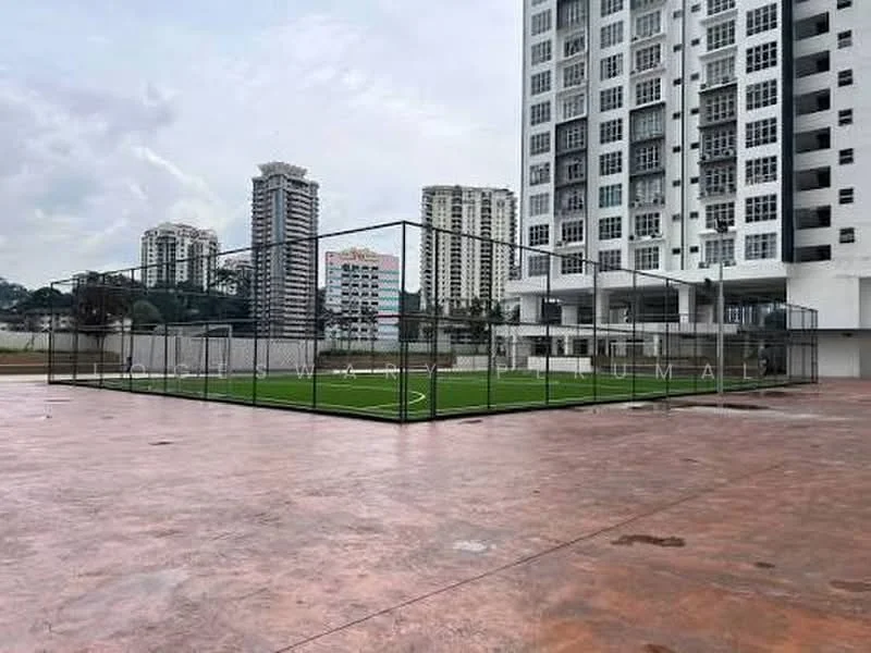 Exterior type: high-rise condominium; features: artificial turf football field, surrounding fence, concrete flooring, multiple high-rise buildings in background, open space, urban setting, cloudy sky; style: modern.