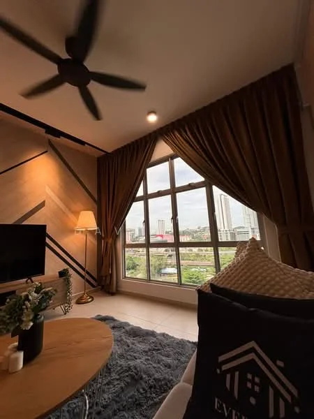 Living features: 5-blade ceiling fan, floor-to-ceiling windows, brown curtains, wooden accent wall with geometric pattern, light-colored walls, light-colored flooring, sofa with decorative cushions, round coffee table, decorative plant on table, lamp beside window, area rug with plush texture, TV console with wall-mounted TV; style: modern; view: city.