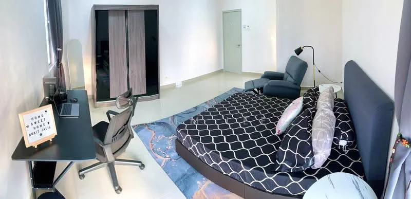 Bedroom features: king-size bed with patterned bedding, upholstered headboard, two decorative pillows, grey armchair, black desk with computer setup, ergonomic office chair, built-in wardrobe with sliding doors, white painted walls, glossy tile flooring, floor lamp, window with sheer curtains; style: modern.