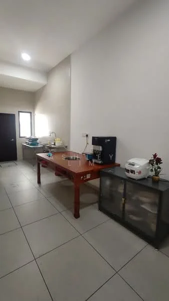 Kitchen features: rectangular wooden dining table, stainless-steel rice cooker, white electric kettle, black refrigerator, glass-front cabinet, white walls, tile flooring, single window, decorative plant in ceramic pot, countertop space, wall-mounted light fixture.