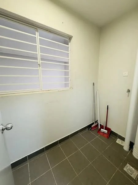 Laundry features: grey tiled flooring, white painted walls, window with security bars, floor drain, cleaning tools (broom and mop), wall-mounted pipe, light fixture.