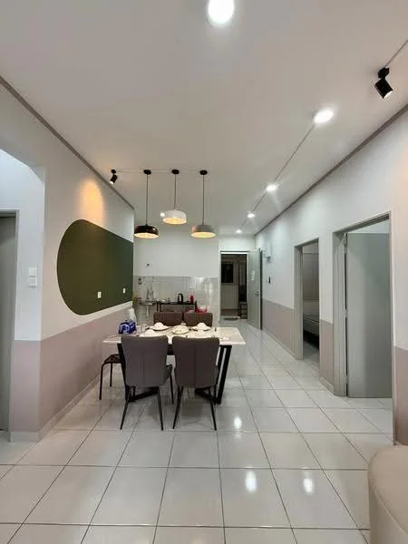 Dining features: rectangular dining table with white top, 4 upholstered dining chairs in grey, pendant lighting with three fixtures, white tiled flooring, green accent wall, cream painted walls, open layout to kitchen, wall-mounted air conditioning unit; style: modern. Kitchen features: kitchen cabinetry with wood finish, stainless-steel sink, built-in stove, kitchen countertop with space for appliances, wall-mounted shelves; style: modern. Hallway features: white painted walls, recessed lighting, doorways leading to other rooms.