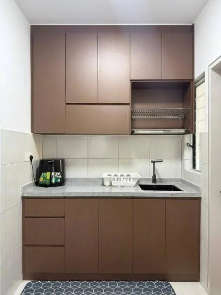Kitchen features: brown cabinetry, grey countertop, single-bowl stainless-steel sink, chrome pull-down faucet, built-in dish rack, black countertop appliance, white tiled backsplash, grey patterned mat; style: modern.