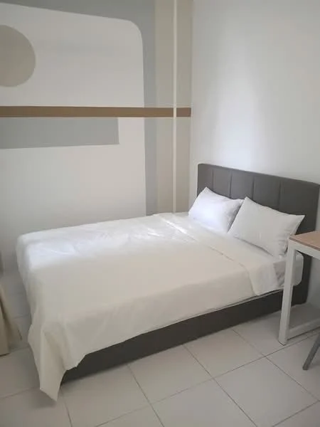 Bedroom features: queen-size bed with grey upholstered headboard, white bedding, white walls, geometric wall design, tile flooring, window with natural light, side table, desk with chair; style: modern.