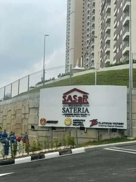 Exterior type: high-rise condominium; features: signage with 'SASAB RESIDENSI SATERIA', landscaped hill, parking area, surrounding fencing, multi-storey building, roadway leading to entrance; style: modern.