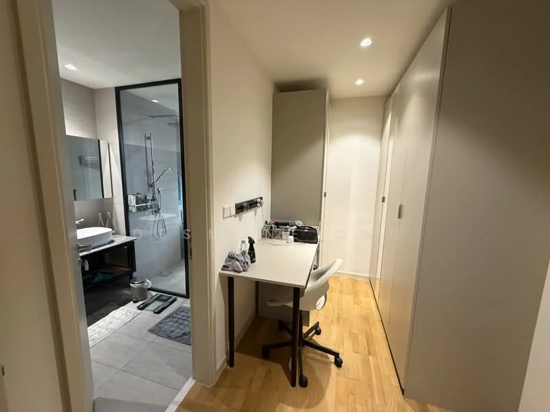 Room features: light wood flooring, white painted walls, built-in cabinets, desk with chair, recessed downlights, doorway leading to bathroom, glass partition wall, neutral color scheme; style: modern.