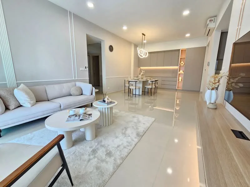Living features: light grey painted walls, polished ceramic tile flooring, 5-blade ceiling fan with light, recessed LED downlights, L-shape sectional sofa in light beige, round coffee table with white top, area rug with soft texture, decorative vase with dried flowers, wall-mounted TV, TV console with wood finish, dining table with 4 upholstered chairs, kitchen cabinetry with integrated lighting; style: modern.