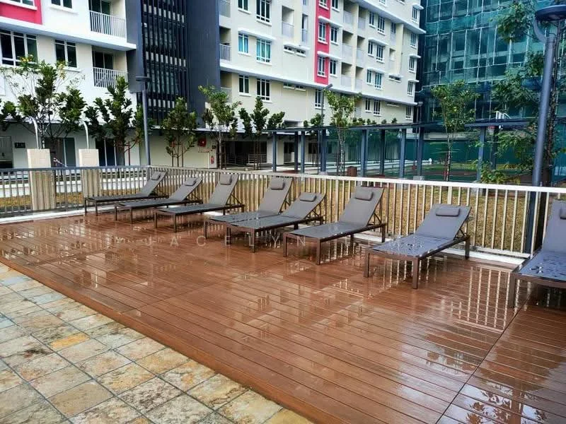 Exterior type: swimming pool deck; features: wooden deck flooring, sun loungers with cushions, surrounding greenery, glass railing, modern architecture in background, paved walkway, planters with small trees; style: modern.