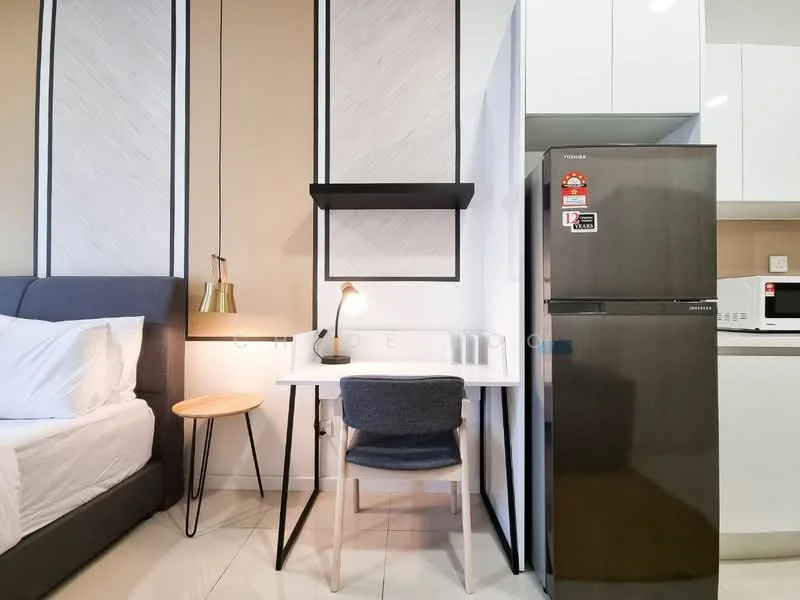 Room features: queen-size bed with white bedding, grey upholstered headboard, small round side table, desk with white surface, grey upholstered chair, black wall-mounted shelf, stainless-steel fridge, built-in white cabinetry, microwave, white tiled flooring, recessed lighting, neutral wall colour; style: modern.