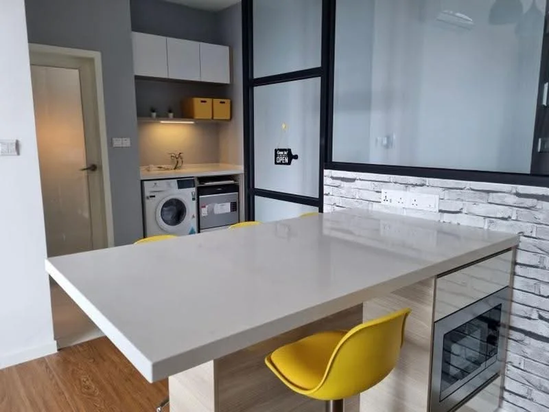 Kitchen features: white quartz countertop, kitchen island with seating, yellow bar stools, built-in oven, stainless-steel microwave, front-load washing machine, white cabinetry, grey accent wall, exposed brick wall, recessed lighting, sliding glass door, wooden flooring; style: modern.