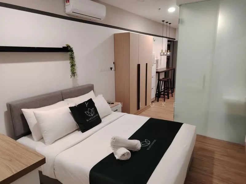 Bedroom features: queen-size bed with white bedding, grey upholstered headboard, 2 white pillows, green accent throw blanket, wooden bedside table, wall-mounted shelf, recessed lighting, air conditioning unit, laminate flooring, glass sliding door, built-in wardrobe, bar stools, kitchenette with refrigerator; style: modern.