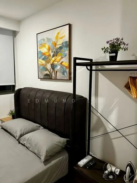 Bedroom features: king-size bed, upholstered headboard in dark grey, grey bedding, framed artwork with floral design, wooden bedside table, decorative plant on bedside table, metal clothing rack, hangers on clothing rack, remote control on bedside table, white walls; style: modern.