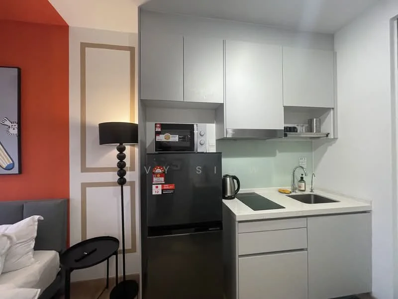 Kitchen features: grey cabinetry, white countertop, single-bowl stainless-steel sink, chrome pull-down faucet, built-in microwave, stainless-steel fridge, electric kettle, 2-burner electric hob, black pendant light, decorative wall paneling in orange and cream, black round side table; style: modern.