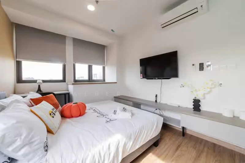 Bedroom features: queen-size bed with white bedding, decorative pillows, wooden flooring, wall-mounted TV, floating TV console, two windows with roller blinds, air conditioning unit, decorative vase with flowers, wall-mounted light switch, neutral wall color; style: modern.