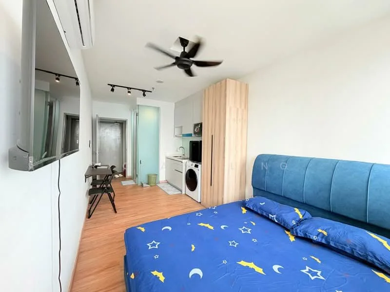 Bedroom features: king-size bed with blue bedding featuring stars, upholstered headboard in blue, wall-mounted TV, 5-blade ceiling fan, wooden flooring, built-in wardrobe in light wood, study desk with chair, kitchenette area with countertop, washing machine, microwave, refrigerator, open layout, air conditioning unit; style: modern.