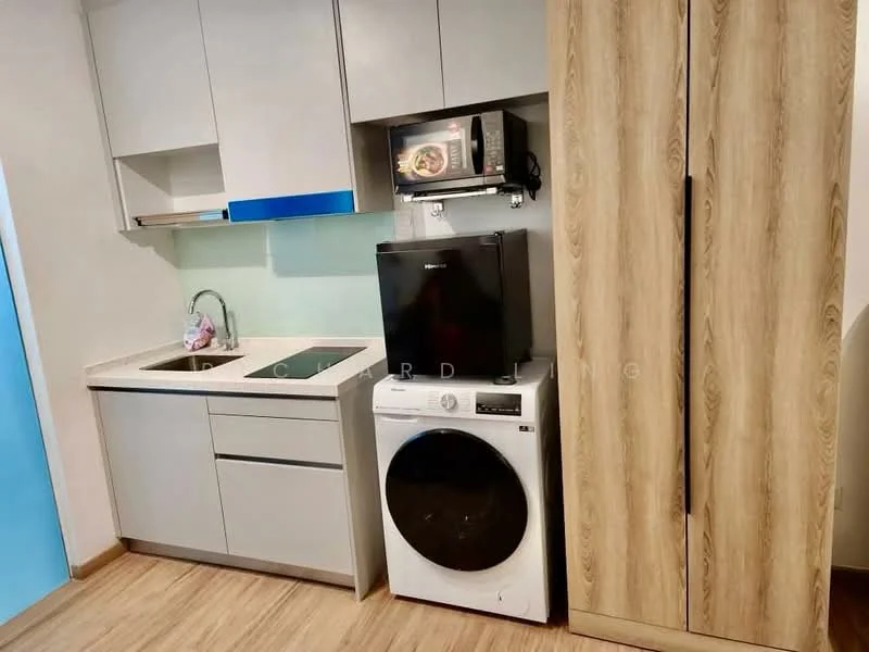 Kitchen features: grey cabinetry, white countertop, single-bowl stainless-steel sink, chrome pull-down faucet, built-in microwave, black refrigerator, front-load washing machine, wooden pantry cabinet, light wood flooring, green backsplash; style: modern.