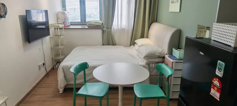 Room features: queen-size bed, upholstered headboard, white bedding, 2 green dining chairs, round white dining table, wall-mounted TV, black fridge, window with sheer curtains, wooden flooring, green accent wall, white bedside table, storage shelf; style: modern.