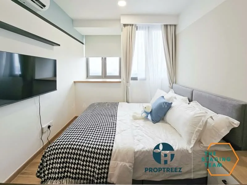 Bedroom features: queen-size bed with white bedding, grey upholstered headboard, black and white patterned throw blanket, two white pillows, wall-mounted flat-screen TV, window with sheer curtains, wooden window sill, light wood flooring, air conditioning unit, decorative teddy bear on bed; style: modern.