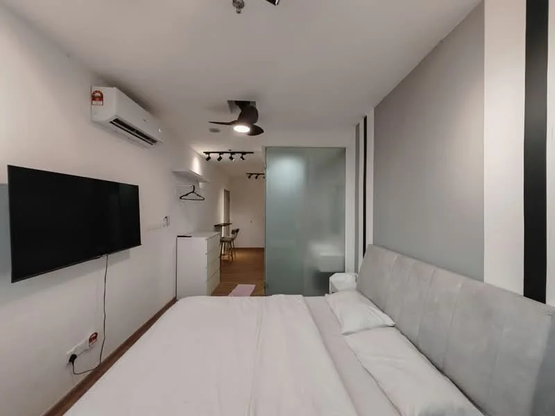 Bedroom features: king-size bed with upholstered headboard, white bedding, wall-mounted TV, 5-blade ceiling fan with light, 1 wall-mounted split AC, grey accent wall, white painted walls, wooden flooring, built-in wardrobe, glass partition leading to bathroom, hanging clothes rack; style: modern.