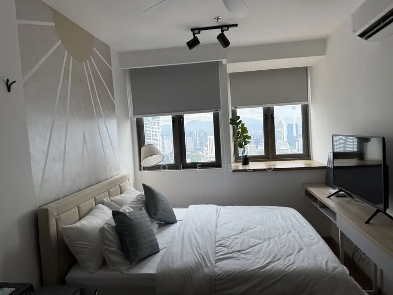 Bedroom features: king-size bed with upholstered headboard, white bedding, two decorative pillows, wall-mounted TV, wooden desk, chair, floor-to-ceiling windows, roller blinds, ceiling fan, decorative wall with sunburst design, green potted plant, city skyline view; style: modern; view: city.