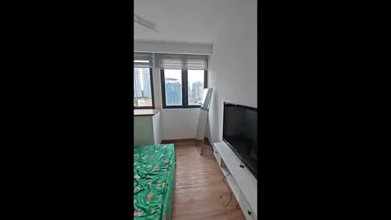 Bedroom features: green patterned bedding, wooden flooring, floor-to-ceiling windows, city skyline view, wall-mounted TV, white painted walls, ceiling fan; style: modern; view: city.
