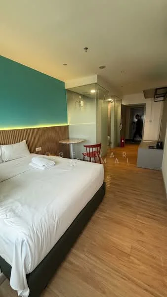 Bedroom features: queen-size bed, white bedding, wooden flooring, blue accent wall, wood paneling behind bed, round dining table, red chair, wall-mounted lighting, glass partition, closet, doorway to hallway, window with natural light; style: modern.