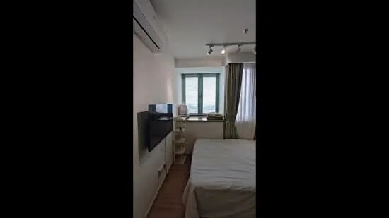 Bedroom features: queen-size bed, wall-mounted TV, 1 wall-mounted split AC, floor-to-ceiling windows, sheer curtains, wooden flooring, light-colored walls, recessed lighting, nightstand, decorative shelving unit; style: modern; view: city.