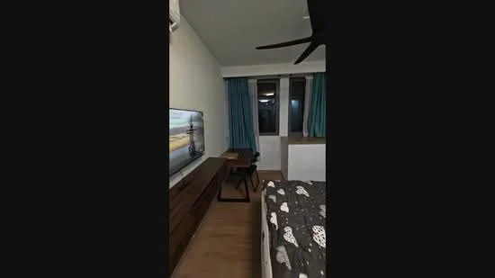 Bedroom features: wooden flooring, white painted walls, floor-to-ceiling windows, blue curtains, queen-size bed with patterned bedding, wall-mounted TV, wooden TV console, study desk with chair, ceiling fan; style: modern.