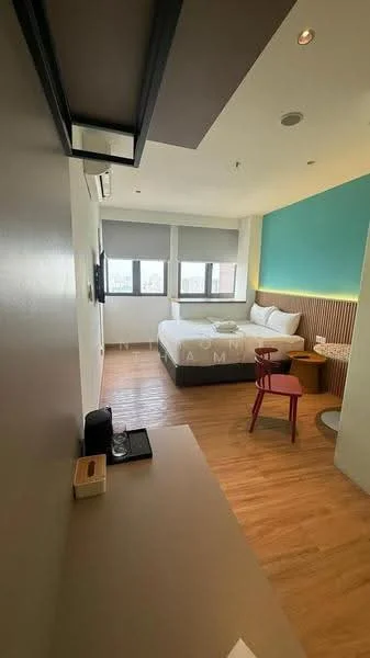 Bedroom features: queen-size bed with white bedding, wooden headboard, two bedside tables, wall-mounted TV, desk with chair, wooden flooring, large windows with roller blinds, accent wall in teal, wood paneling behind the bed, air conditioning unit, decorative wall light; style: modern; view: city.
