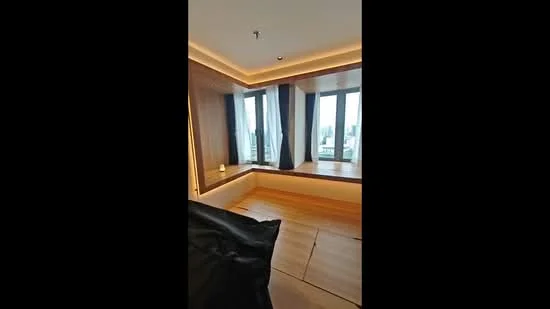 Bedroom features: wooden flooring, tray ceiling with recessed lighting, floor-to-ceiling windows, blackout curtains, window seat with built-in storage, decorative wall paneling, LED strip lighting, city view; style: modern; view: city.