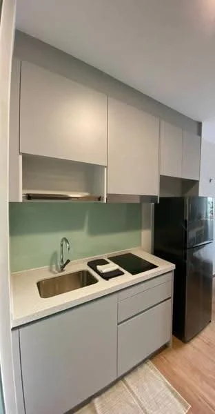 Kitchen features: grey flat-panel cabinets, white quartz countertop, single-bowl stainless-steel sink, chrome pull-down faucet, black built-in induction hob, black refrigerator, green backsplash, wooden flooring, under-cabinet lighting; style: modern.