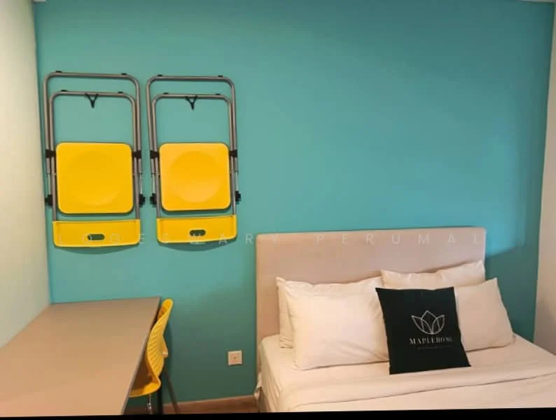 Bedroom features: turquoise painted walls, single bed with white bedding, upholstered headboard, study desk with light wood finish, yellow folding chairs mounted on wall, decorative pillow with logo, wooden flooring, window with natural light; style: modern.