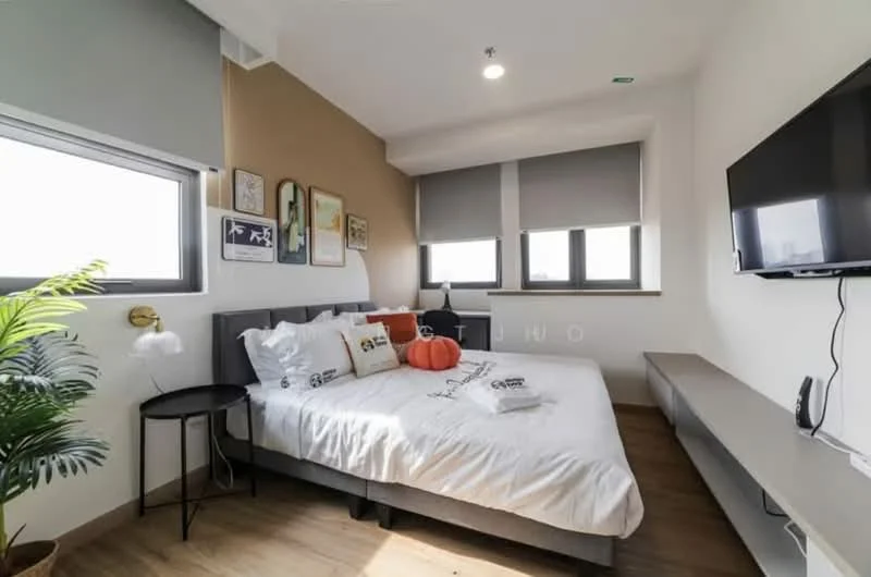 Bedroom features: king-size bed with white bedding, upholstered headboard, two orange decorative pillows, nightstand with black finish, table lamp with white shade, wall-mounted TV, floating shelf under TV, large windows with roller blinds, wooden flooring, decorative wall art, green potted plant; style: modern; view: city.