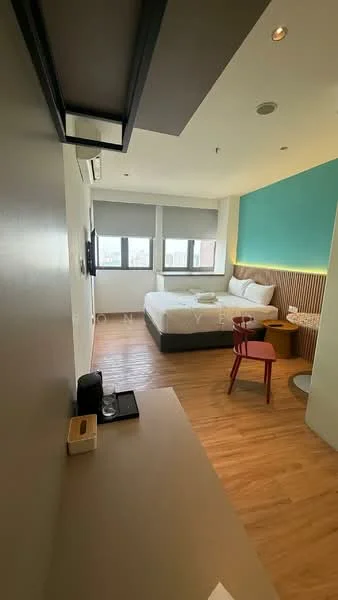 Bedroom features: queen-size bed with white bedding, wooden headboard, wooden flooring, wall-mounted TV, desk with chair, small round side table, air conditioning unit, two windows with roller blinds, accent wall in teal, wood paneling behind the bed, decorative wall light, open shelving unit; style: modern; view: city.