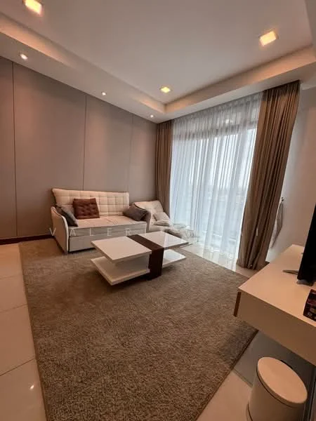 Living features: cream painted walls, white ceiling with recessed lighting, floor-to-ceiling windows with sheer curtains, 3-seater fabric sofa in light grey, accent cushions in brown, white coffee table with wooden accents, area rug with neutral tones, TV console with flat-screen TV, decorative wall art, light-colored flooring, wall-mounted lighting fixtures; style: modern; view: city.