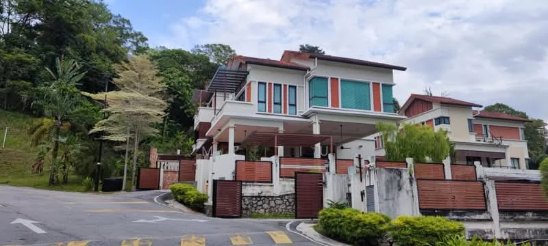 Exterior type: detached bungalow; features: two-storey building, white painted facade, red accent panels, large windows with green shutters, covered car porch, manicured lawn, surrounded by trees, sloped driveway, balcony on upper floor, gated entry; style: modern.