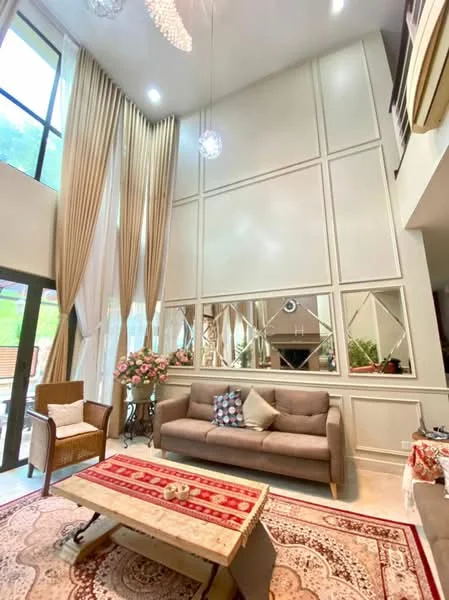 Living features: high ceiling, cream painted walls, mirrored wall panels, large windows with sheer curtains, chandelier lighting, 5-blade ceiling fan, 3-seater fabric sofa in grey, decorative throw pillows, area rug with intricate pattern, coffee table with wood finish, potted flowers on side table, wooden armchair, wall-mounted decor, recessed lighting; style: modern; view: garden.