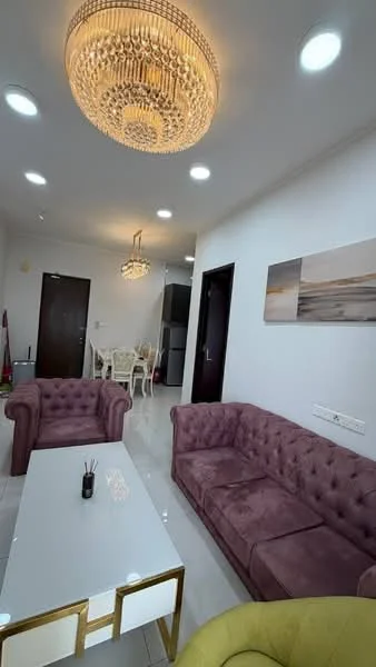 Living features: chandelier with crystals, recessed LED downlights, purple tufted fabric sofa, green accent chair, white coffee table with gold accents, cream tiled flooring, wall-mounted artwork, open layout to dining area; style: modern.